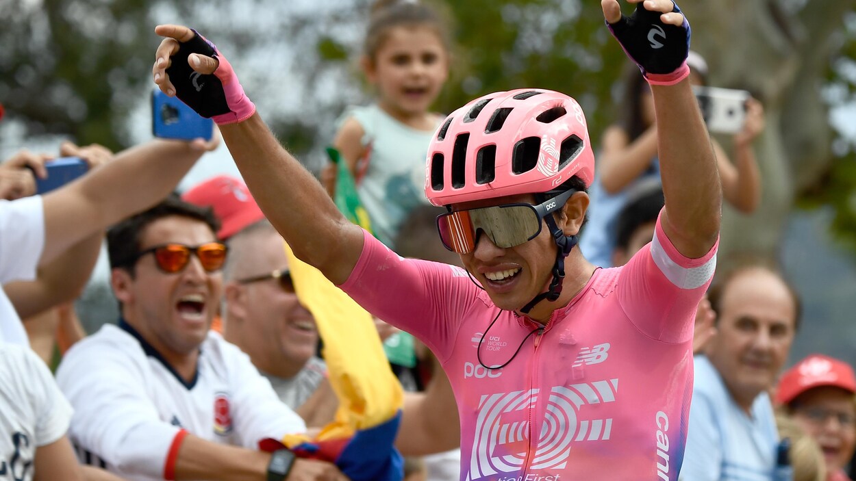 Un coureur cycliste lève les bras en triomphe devant une foule compacte.