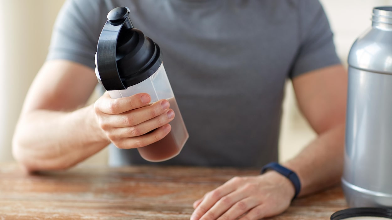 Un homme tient dans sa main une boisson sportive.