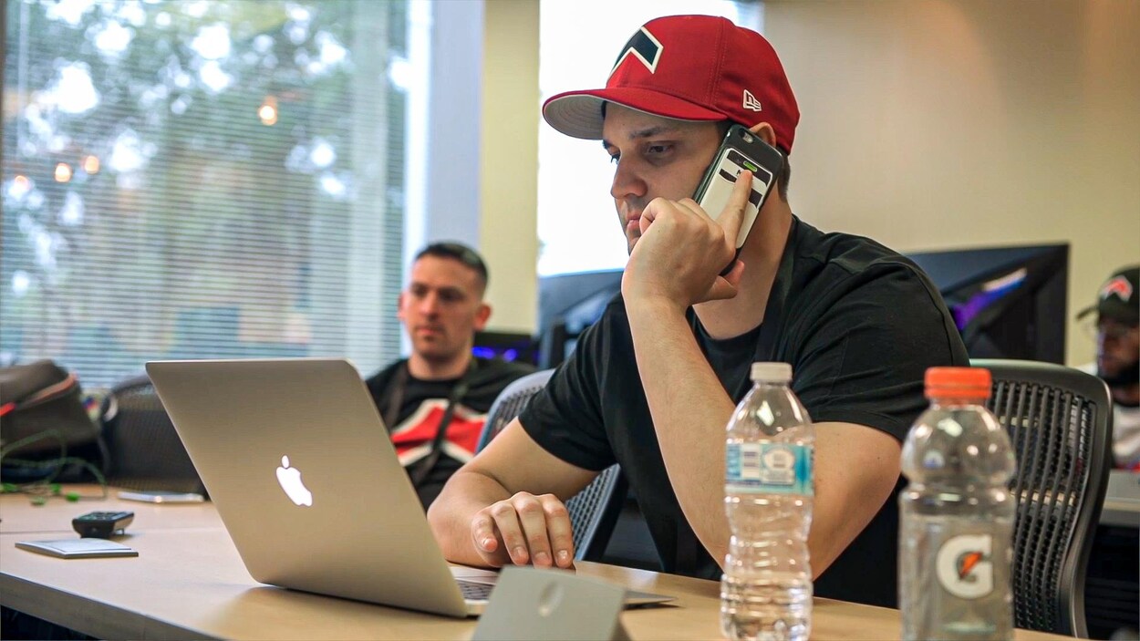Shane Talbot discute au téléphone tout en travaillant à l'ordinateur.