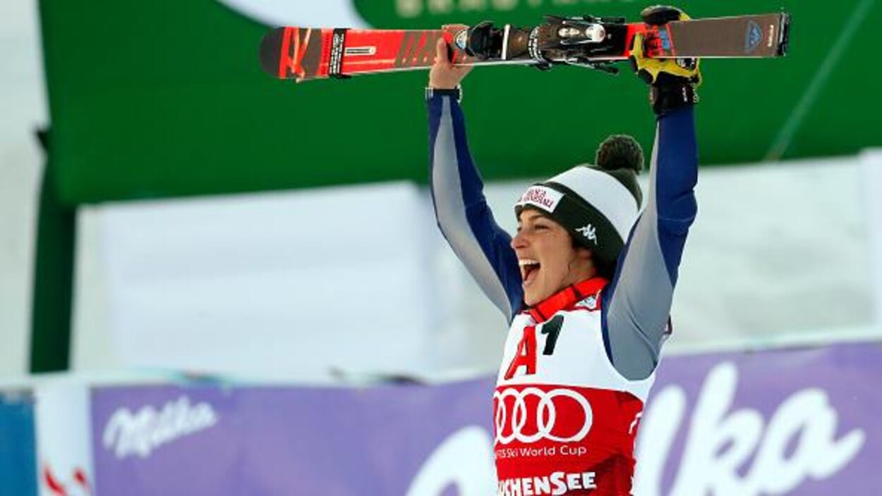 Elle brandit ses skis au-dessus de sa tête en signe de victoire.