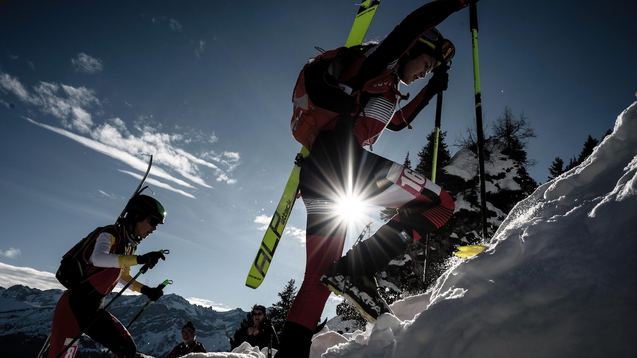 Deux skieuses montent une pente à pied.