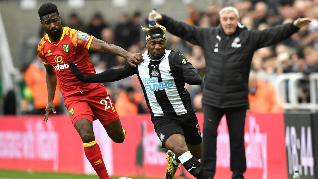 Un joueur de Norwich tente d'en retenir un autre de Newcastle pendant un match.