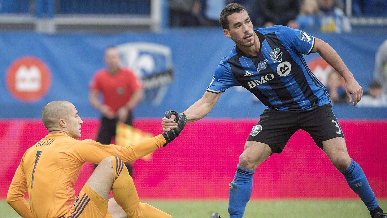 Daniel Lovitz (à droite), de l'Impact de Montréal, aide son coéquipier Evan Bush à se relever.