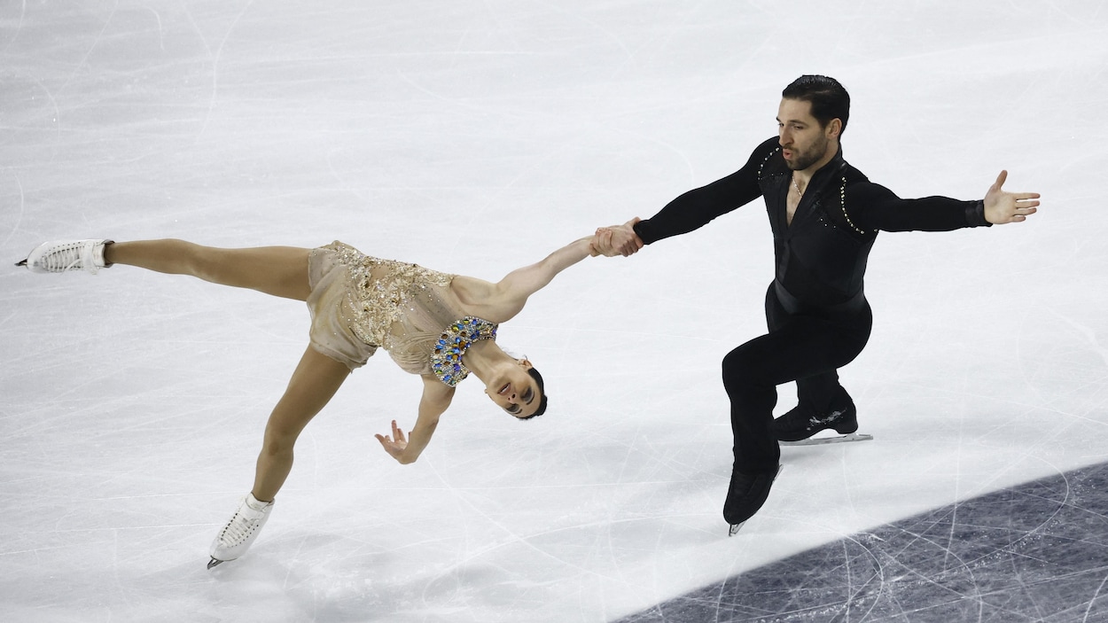Les patineurs canadiens Deanna Stellato-Dudek et Maxime Deschamps se tiennent par la main, en équilibre, sur la glace. 