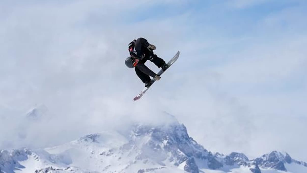 Pendant un saut, il tient le milieu de sa planche de la main droite.