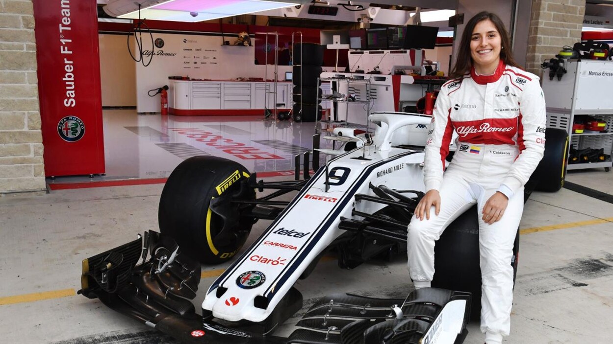 Elle est assise sur la roue avant gauche de sa voiture.