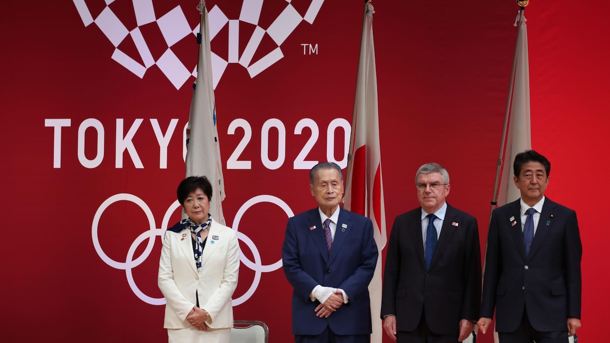Ils se tiennent debout lors d'une conférence de presse. Derrière eux, le logo des Jeux olympiques de Tokyo 2020.