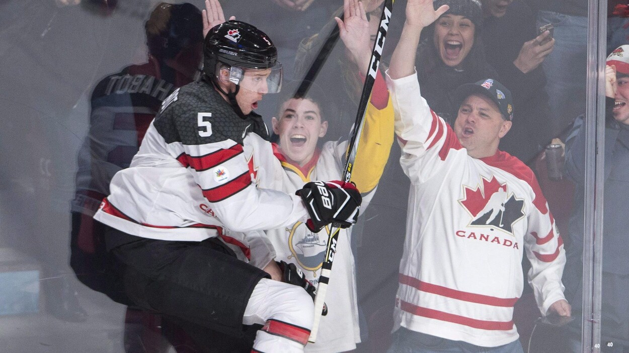 Thomas Chabot saute dans la baie vitrée devant deux amateurs, après un but de l'équipe canadienne.