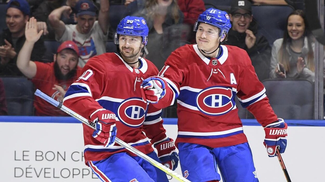 Ils sont côte à côte sur la patinoire et sourient.