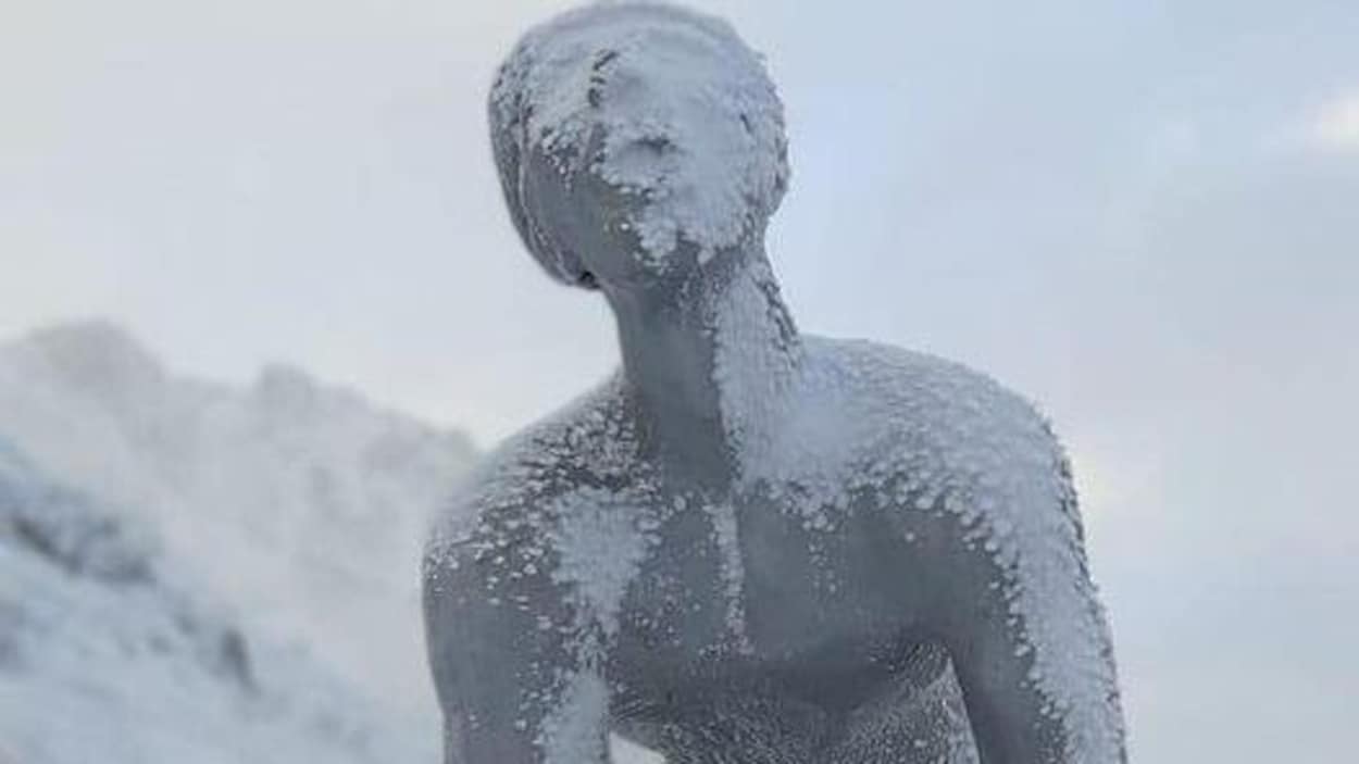Une statue représentant un cycliste en plein effort est recouverte de neige.