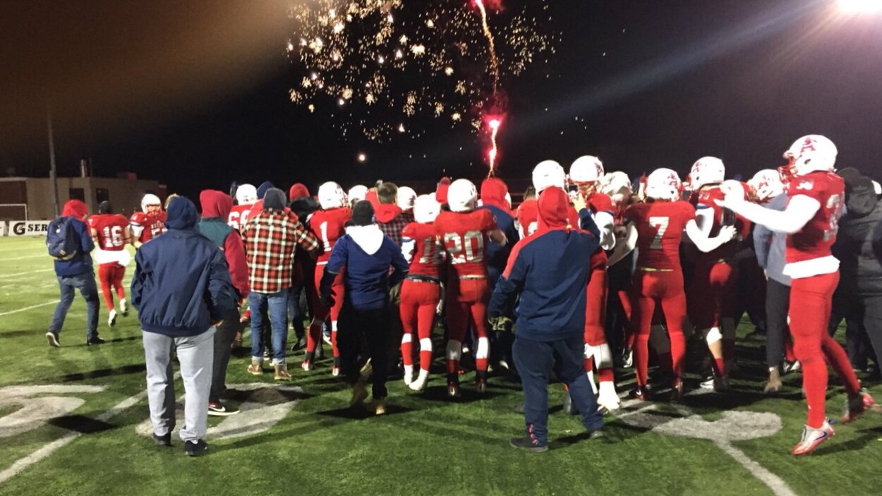 L'équipe de football de l'Université Acadia célèbre sur la terrain après avoir remporté la Coupe Loney. En arrière-plan, on voit des feux d'artifice. L'équipe de football de l'Université Acadia célèbre sur la terrain après avoir remporté la Coupe Loney. En arrière-plan, on voit des feux d'artifice.