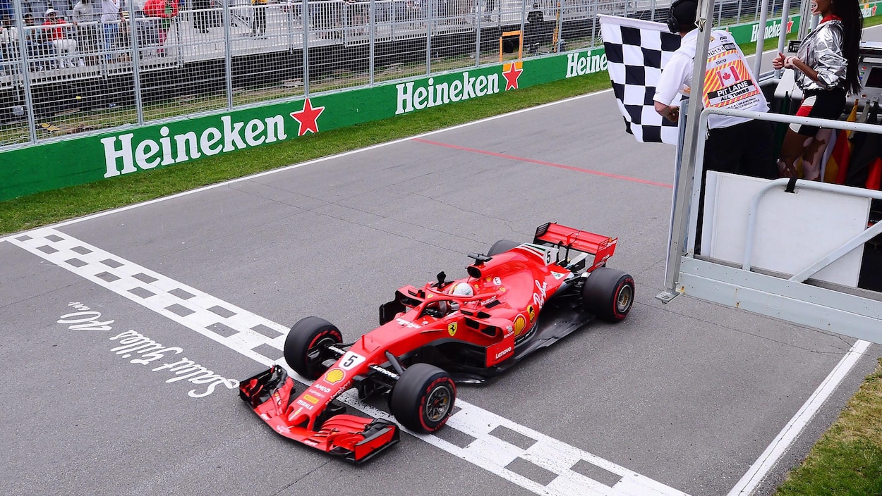 Le pilote Ferrari traverse la ligne d'arrivée sous le drapeau à damier pour remporter le Grand Prix.