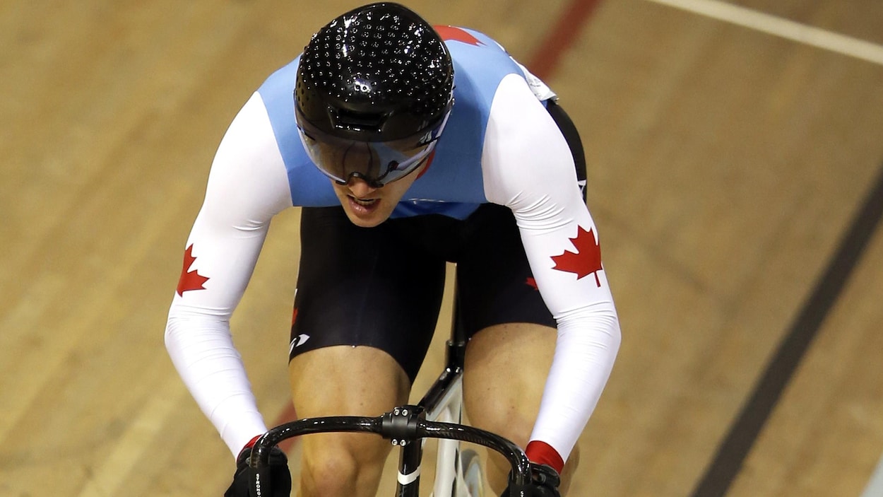 Le cycliste est en plein effort sur la piste.