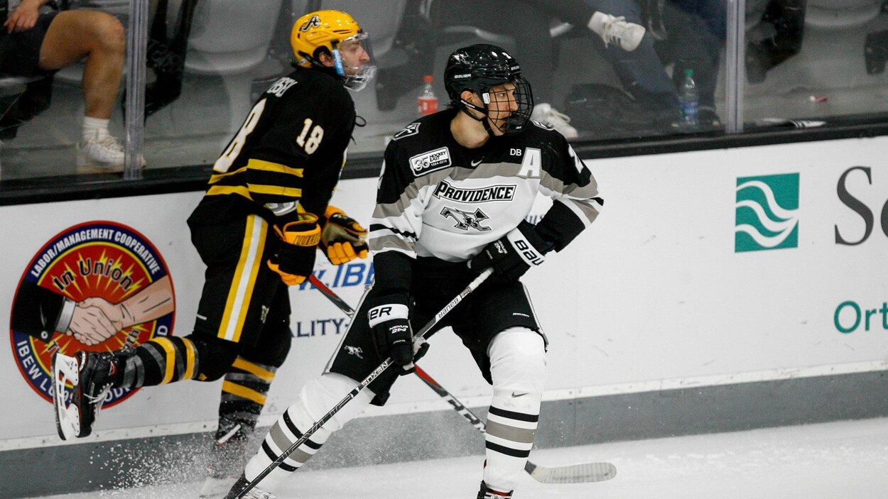 Vincent Desharnais bloque un adversaire durant un match de hockey universitaire.