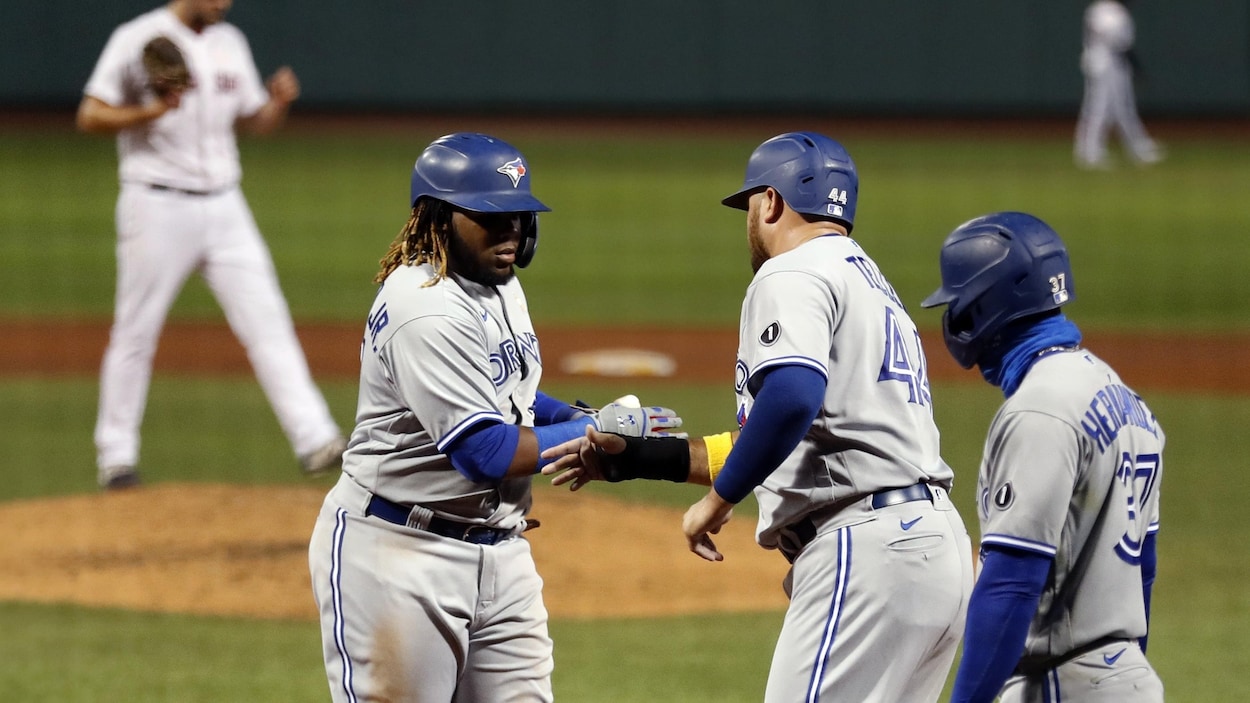 Trois coéquipiers se félicitent après qu'un d'eux eut marqué un point dans un match de baseball.