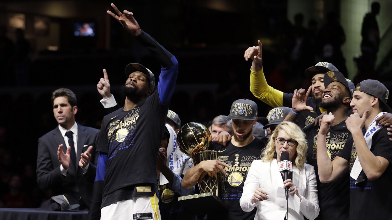 Les joueurs des Warriors de Golden State fêtent une scène alors que Kevin Durant (à gauche) salue la foule avec son trophée de joueur par excellence dans la main droite.