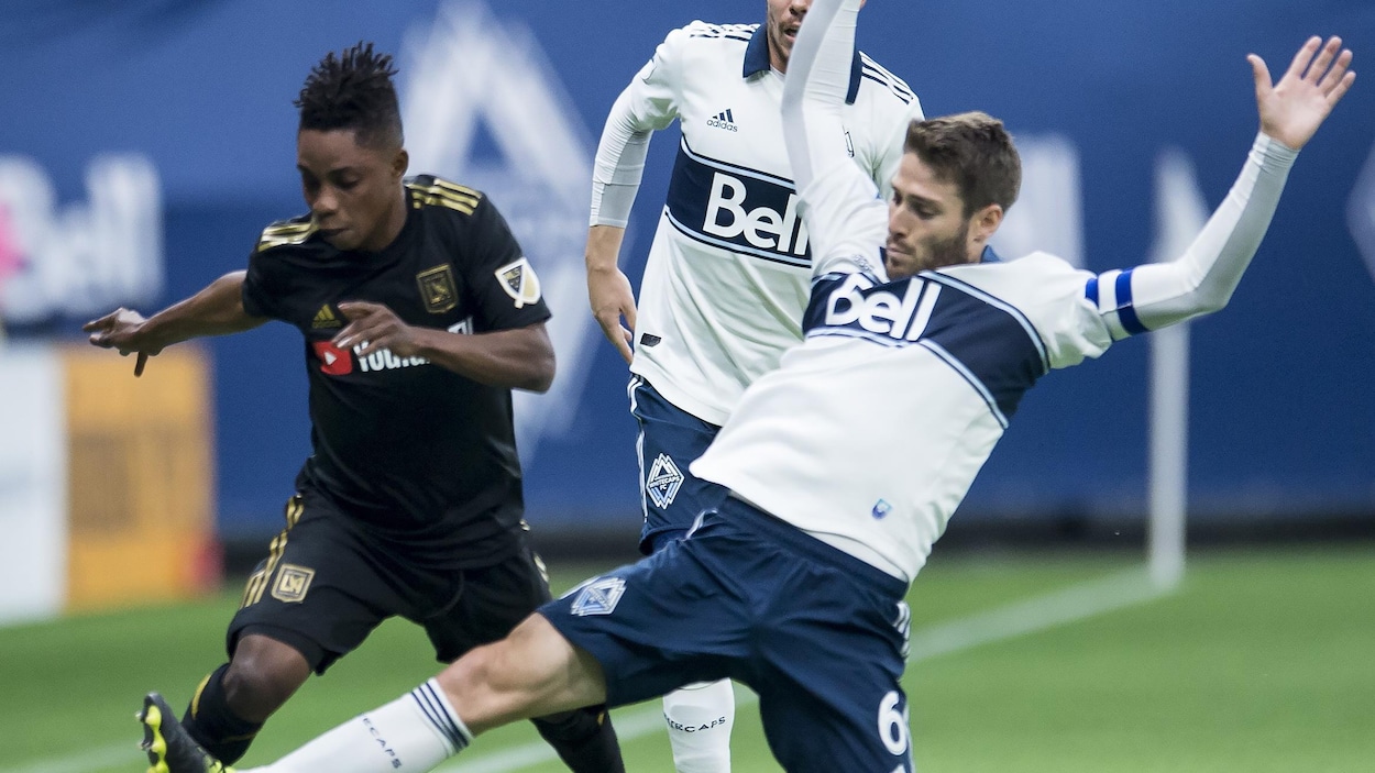 Un joueur des Whitecaps se bat pour la possession du ballon avec son adversaire du FC Los Angeles. Il glisse sa jambe vers le ballon.