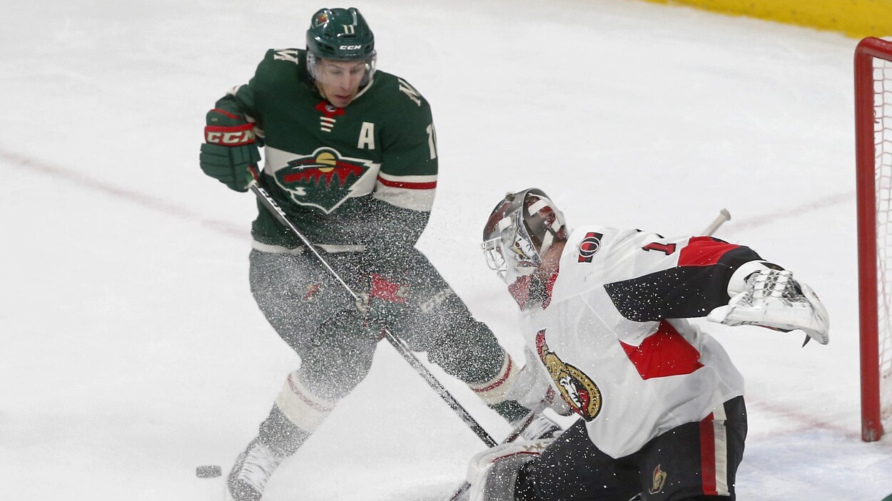 Zach Parisé freine devant Mike Condon. Zach Parisé freine devant Mike Condon.