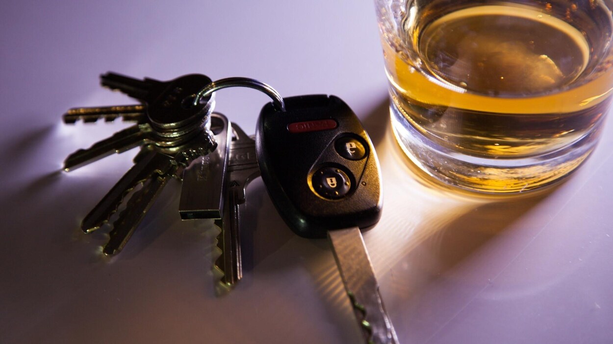 Des clés à côté d'un verre d'alcool.