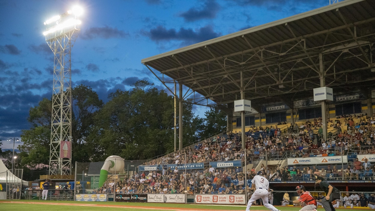 Image d'u stade de baseball avec une foule qui remplit les sièges des estrades, et des joueurs sur le terrain.