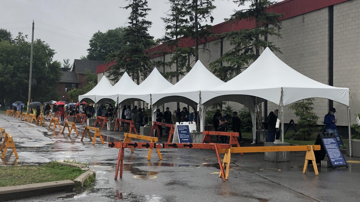 Des gens font la file sous des tentes à l'aréna Brewer à Ottawa.