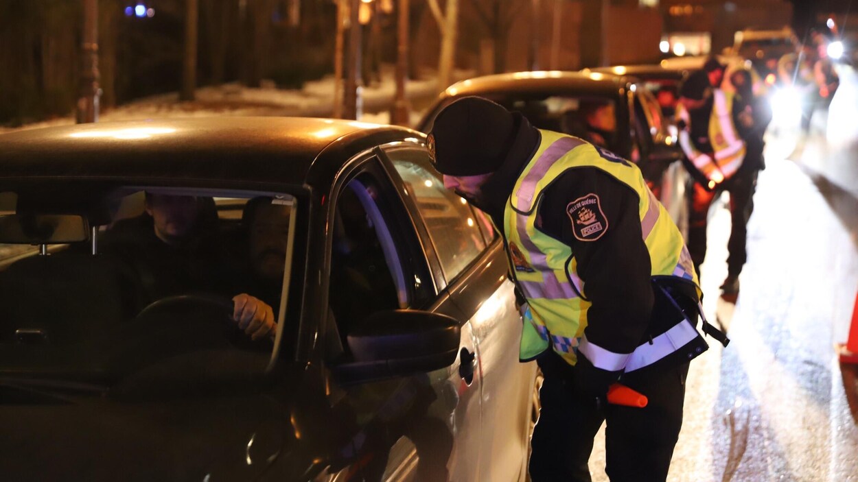 Une file des voitures arrêtées par des policiers dans la nuit.