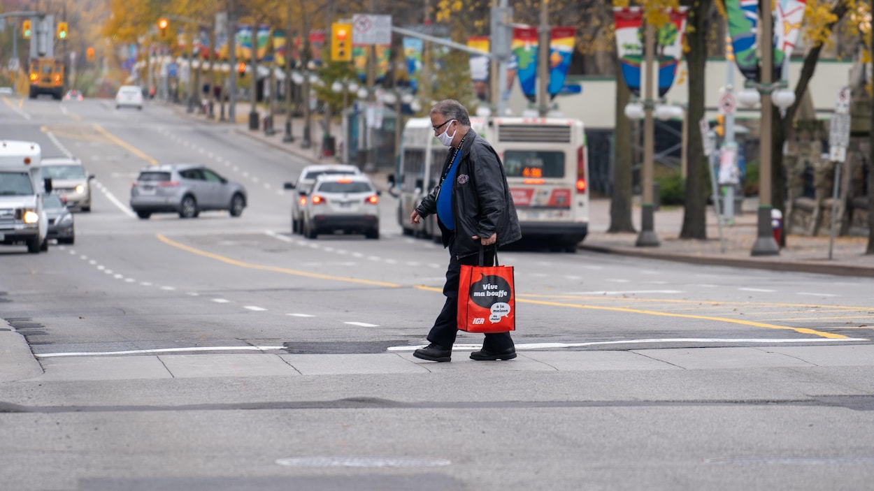 Un résident, portant le masque, traverse une rue du centre-ville.