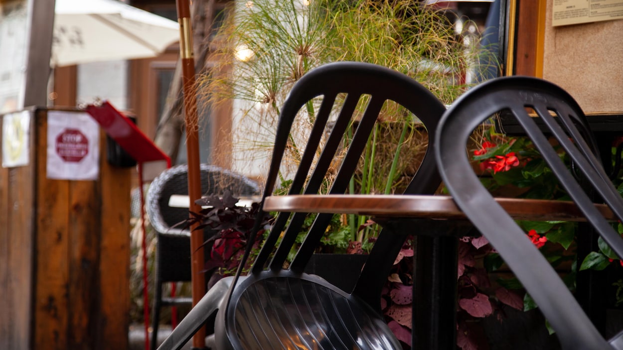 Deux chaises sont accotées sur une table de terrasse.