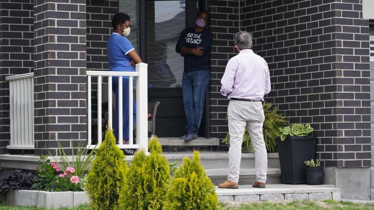 Des gens s'entretiennent à la porte d'une maison.
