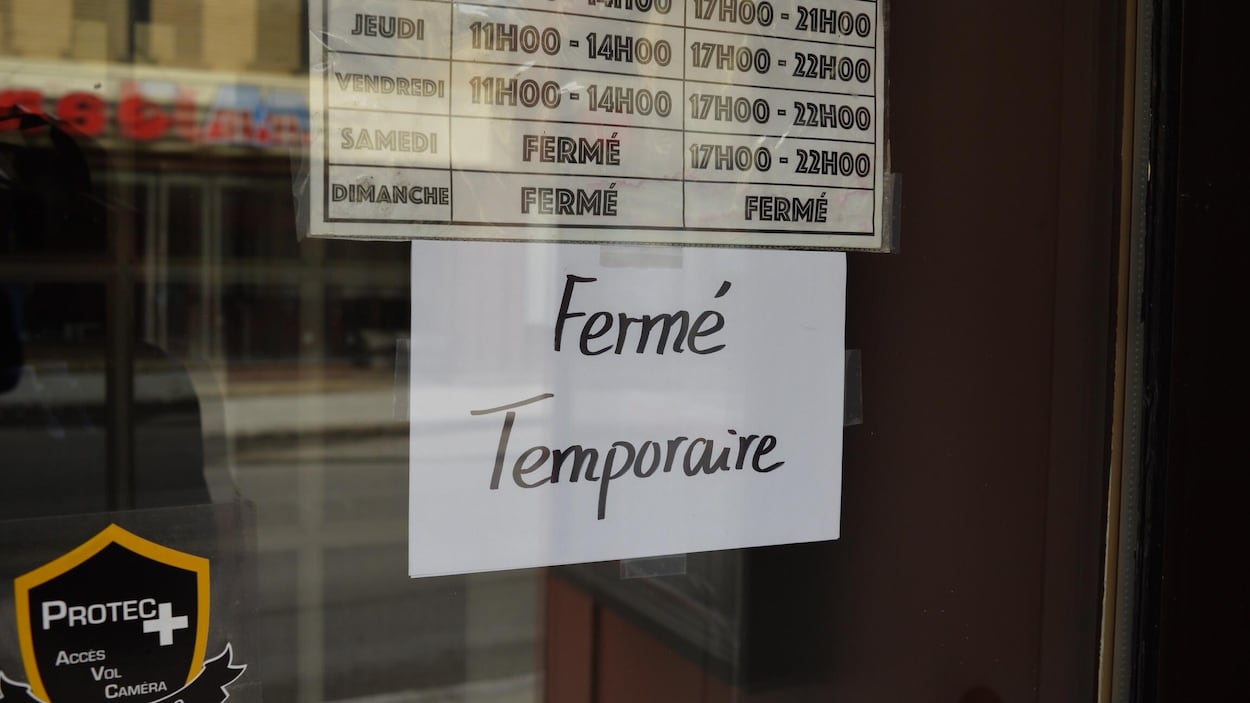 Une affiche « Fermé temporaire » dans la porte d'un commerce fermé en raison de la pandémie de COVID-19 à Québec.