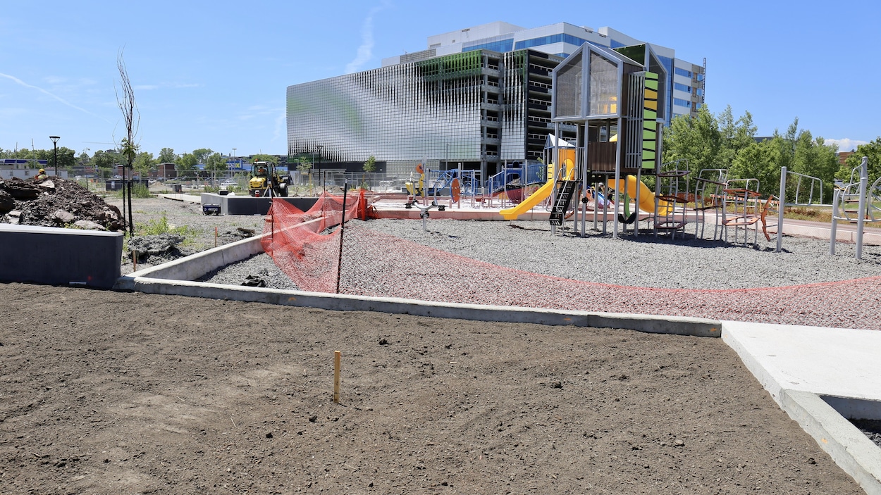 À l'arrière-plan : un immeuble en construction... devant : un module de jeux pour enfant fraîchement installé.