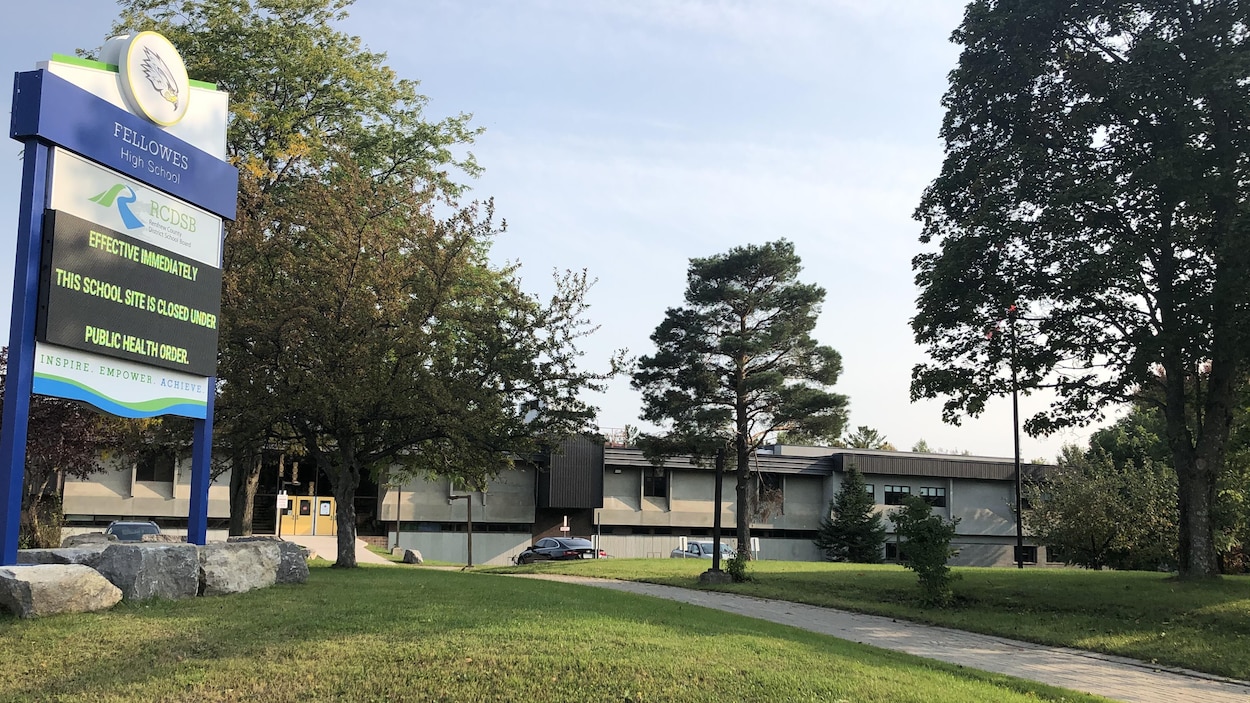 Affiche de l'école et l'édifice en arrière plan.