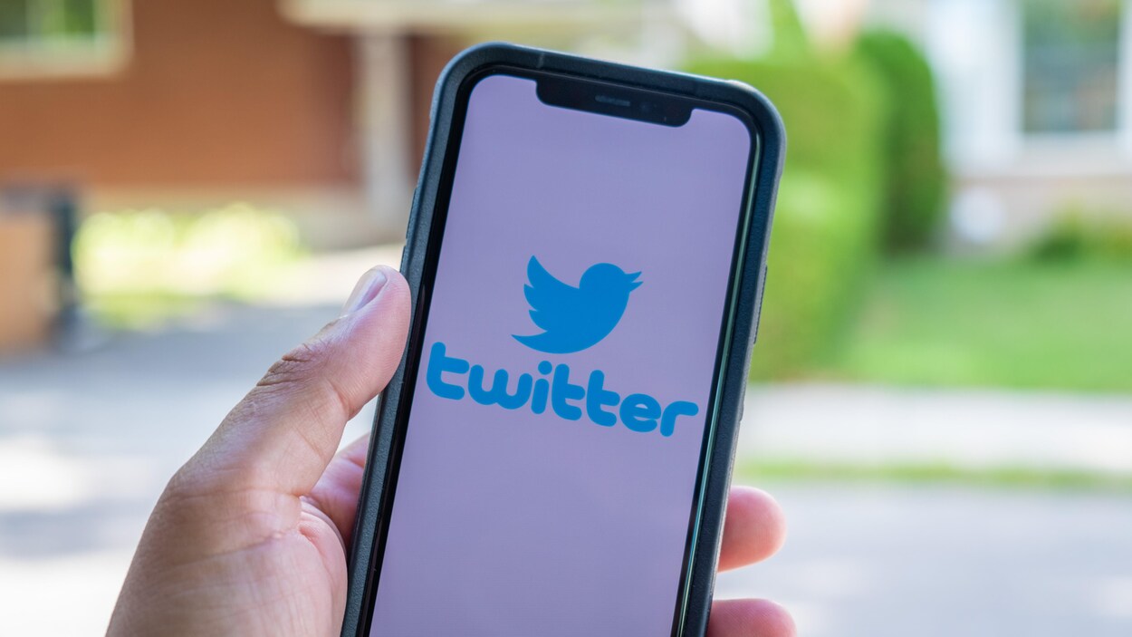 Une main tient un téléphone intelligent sur lequel on voit l’application Twitter.