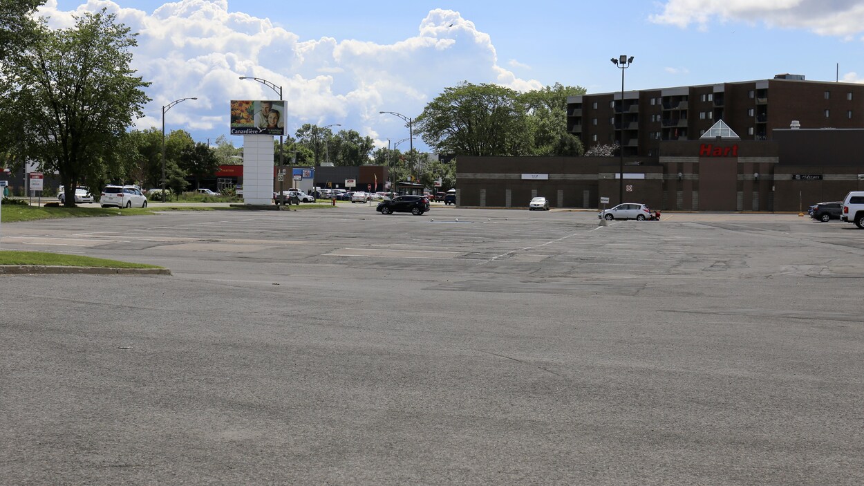 Un plan large d'un petit centre commercial, avec un grand stationnement presque vide