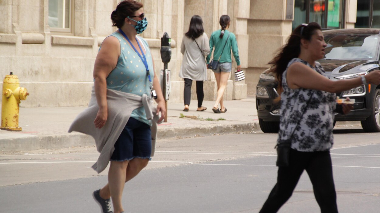 Deux femmes marchent dans la rue à Regina. L'une d'elles porte un masque.