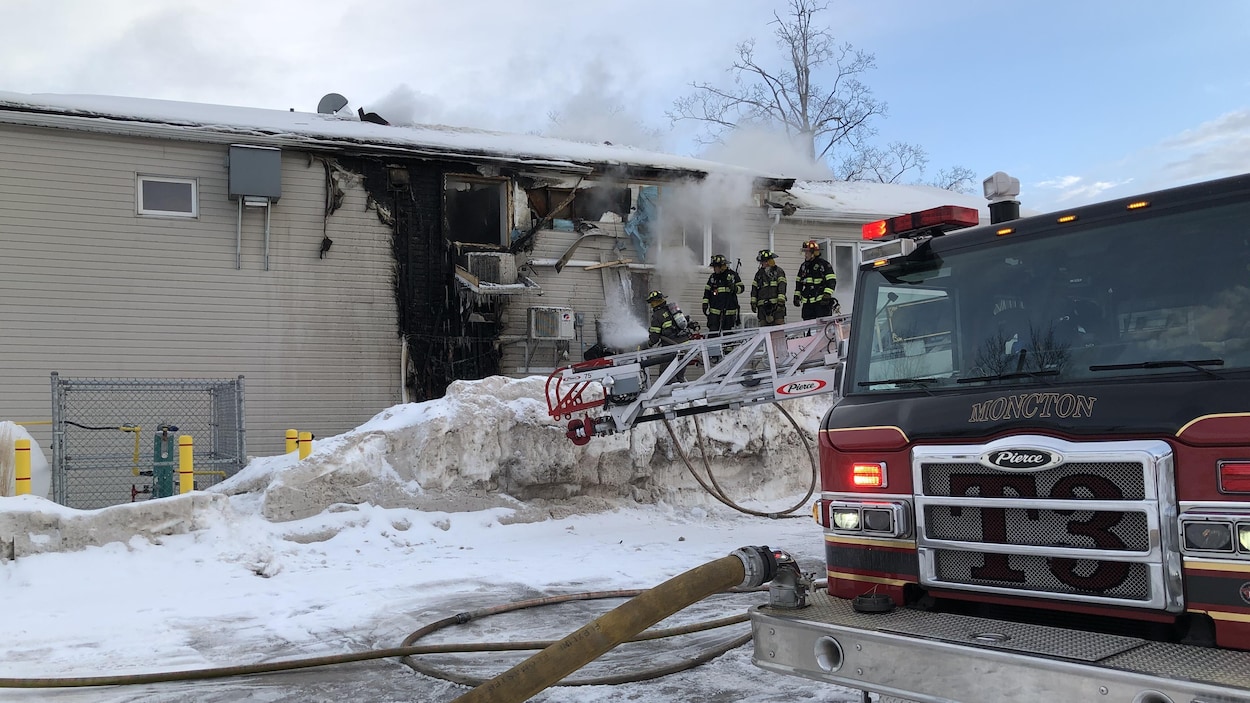 Quatre pompiers examinent les dégâts de l'édifice.