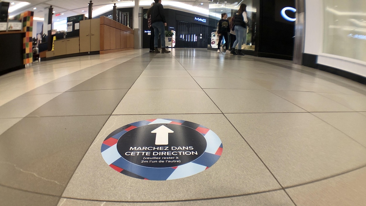 Quelques personnes dans un couloir examinent la vitrine d'une boutique.