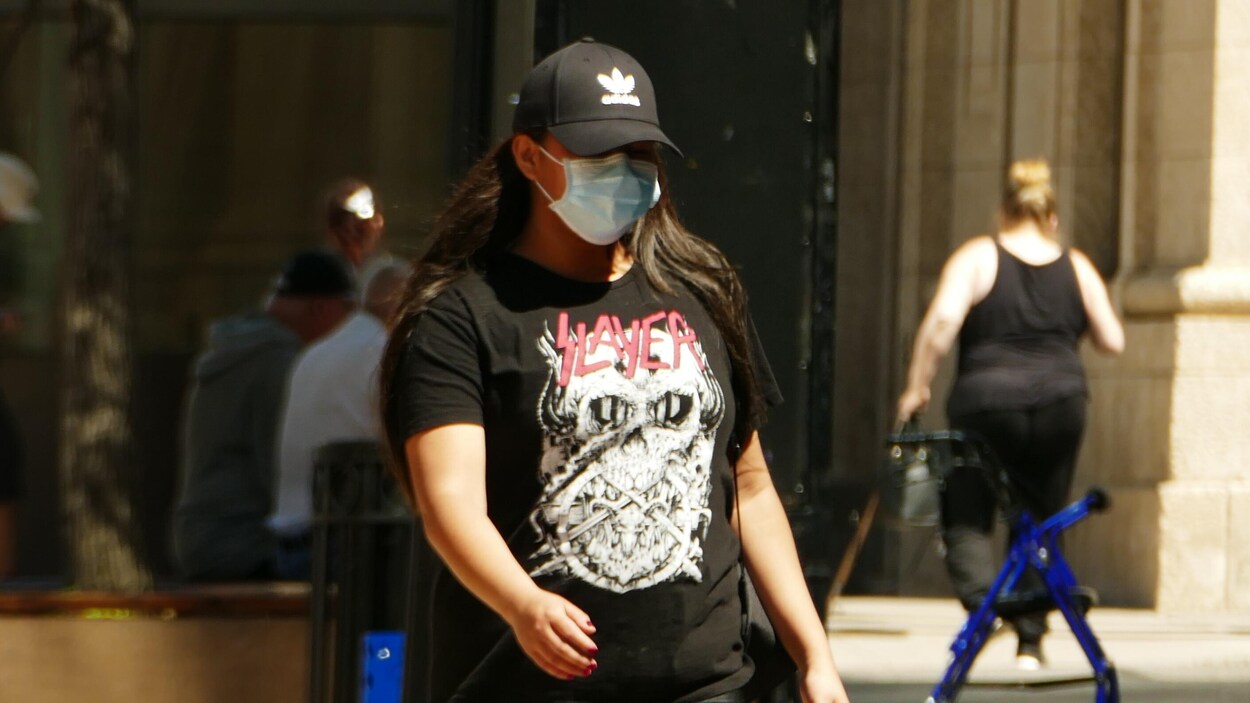 Une personne portant un masque marche dans les rues de Regina.