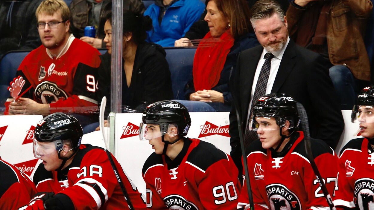 Des joueurs de hockey sur un banc avec Patrick Roy, l'air grave, à l'arrière