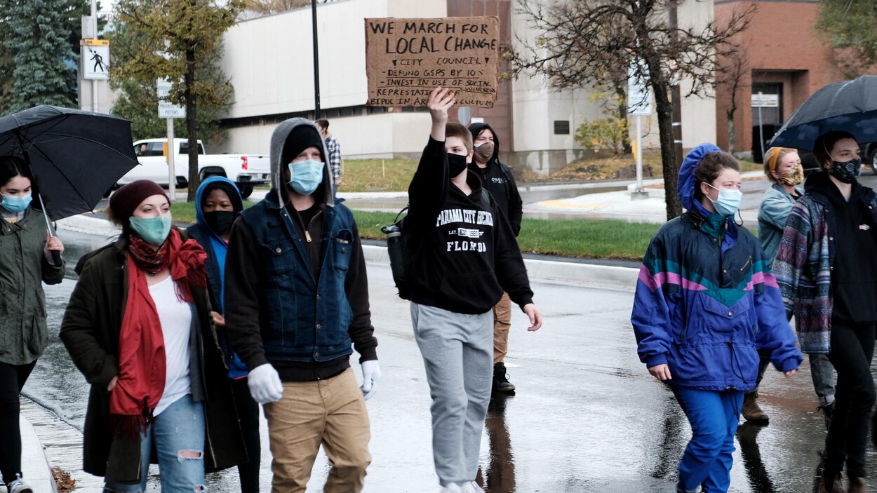 Des manifestants marchent dans la rue en tendant des affiches