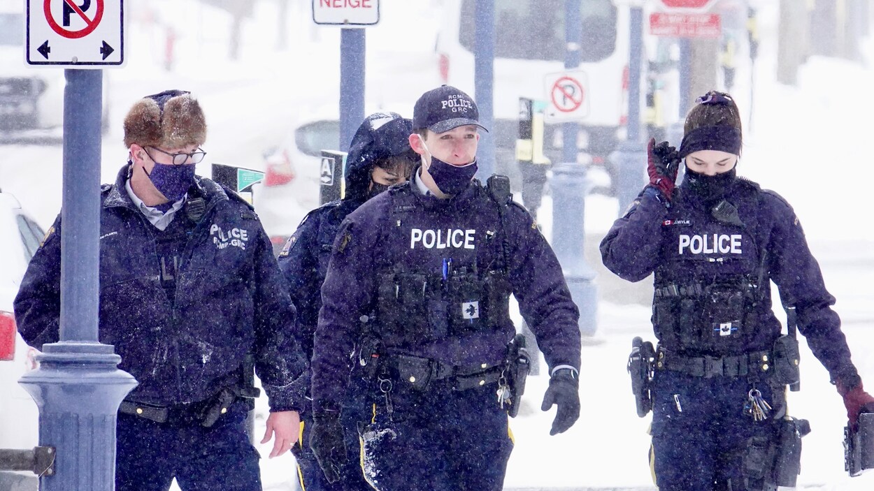 Quatre policiers de la GRC marchent sous la neige.