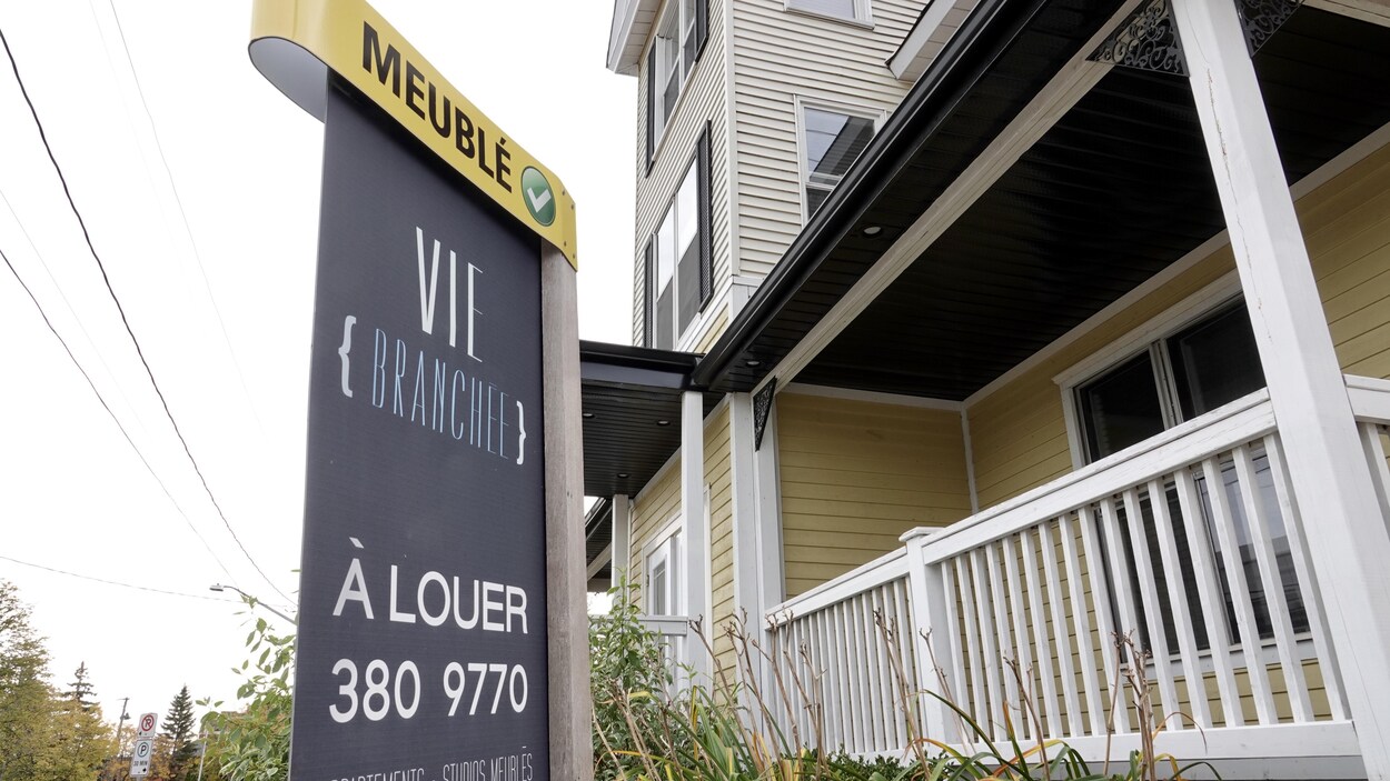 Affiche de logement à louer devant un immeuble.