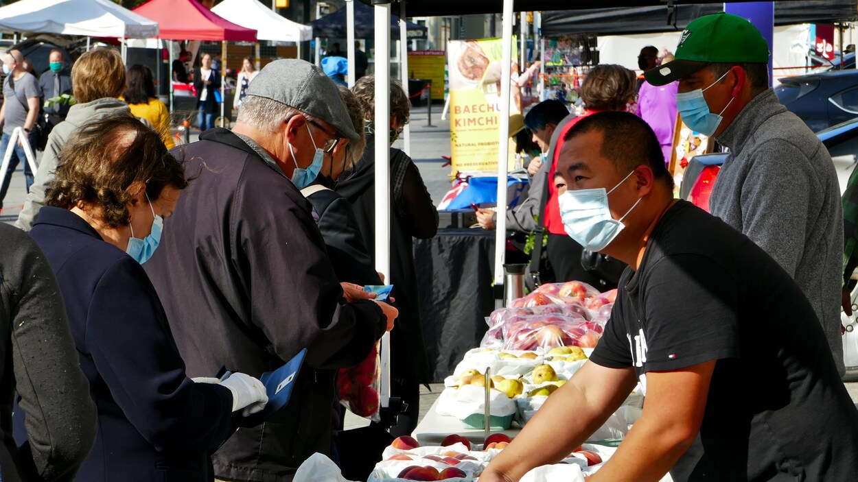 Des gens portant des masques au marché des fermiers de Regina en automne.