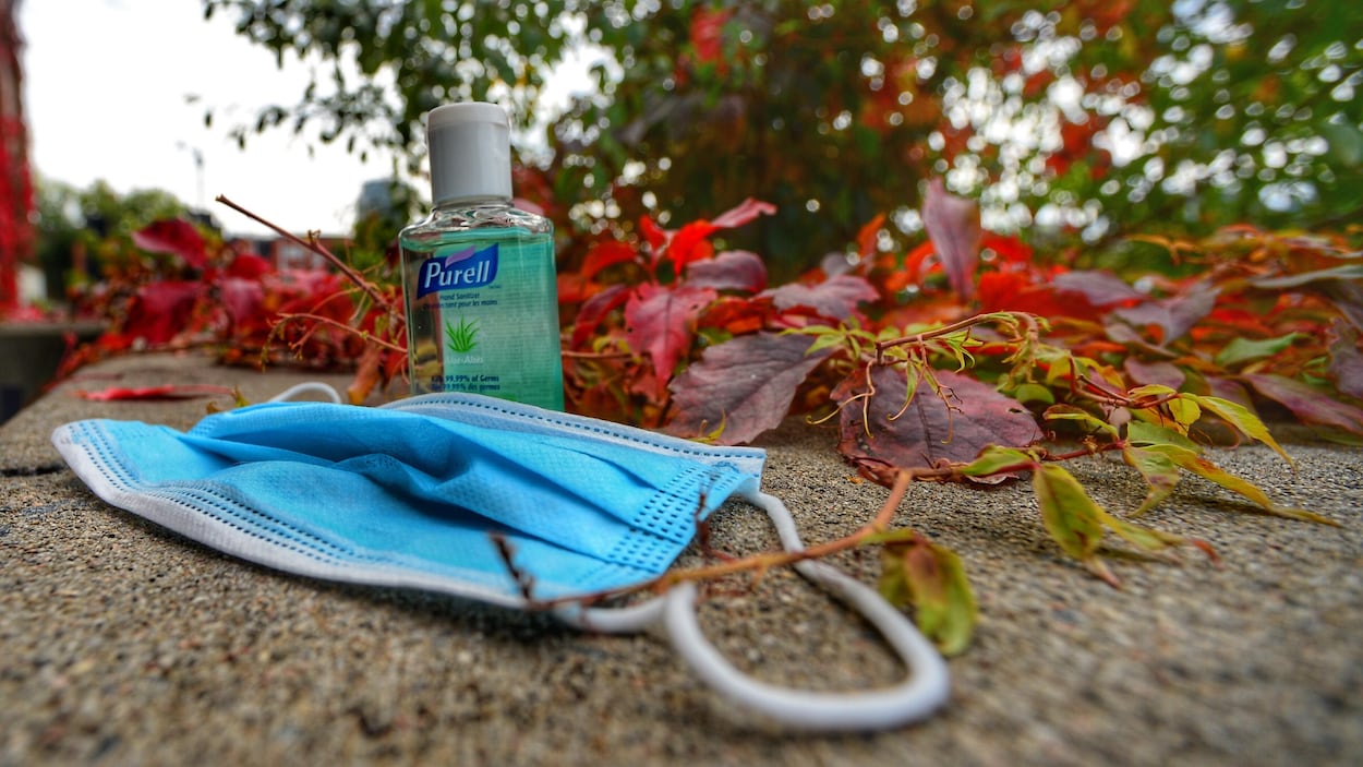 Nature morte avec un masque hygiénique et une bouteille de désinfectant dans les feuilles d'automne.