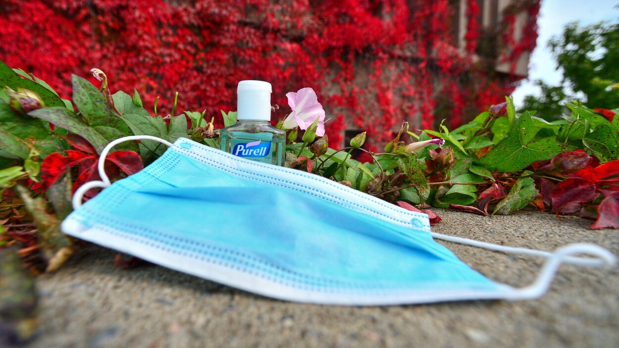 Un masque et une bouteille de désinfectant sur le sol.
