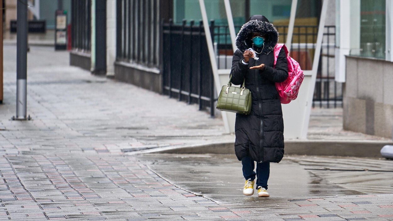 Une femme portant un masque se désinfecte les mains dans la rue