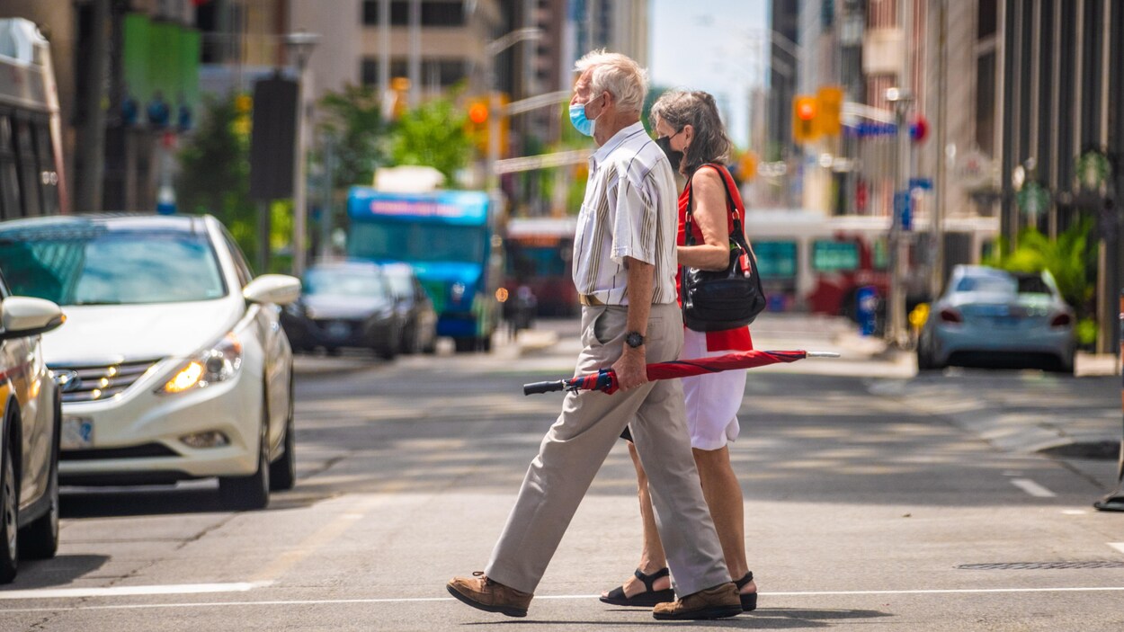 Un couple portant le masque traverse la rue à Ottawa.