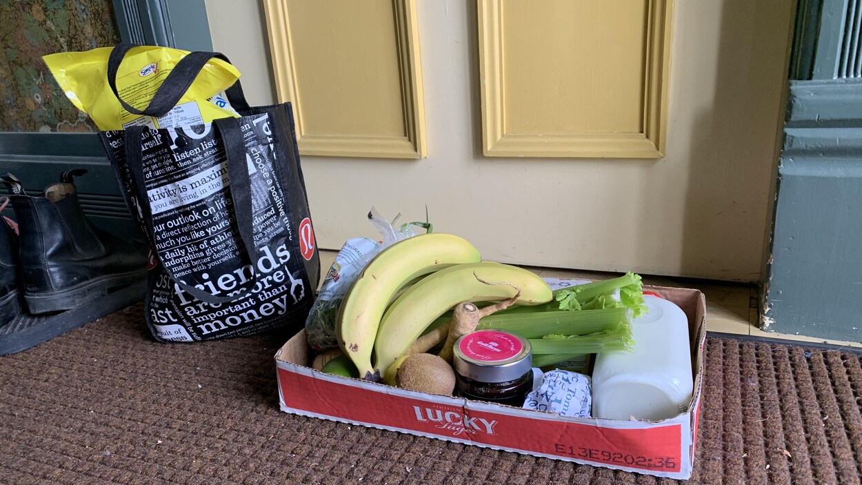 Un carton et un sac d'épicerie sont déposés devant une porte fermée.