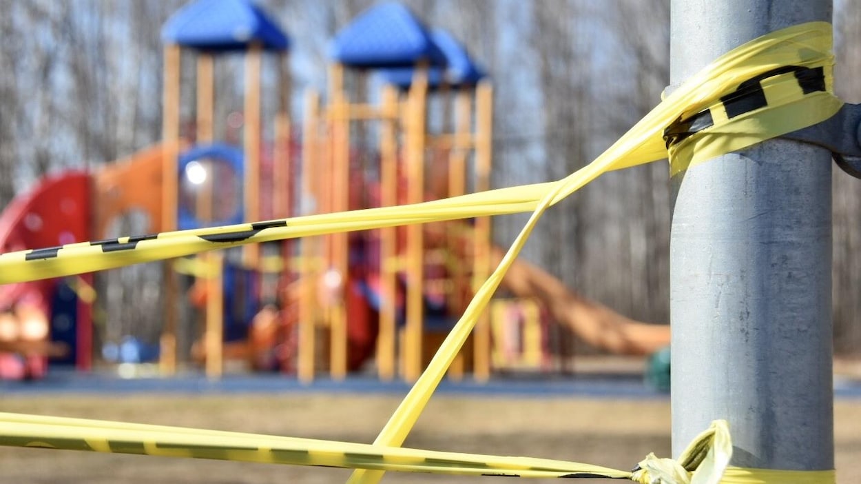 Du ruban jaune bloque l'accès à des jeux pour enfants dans un parc.