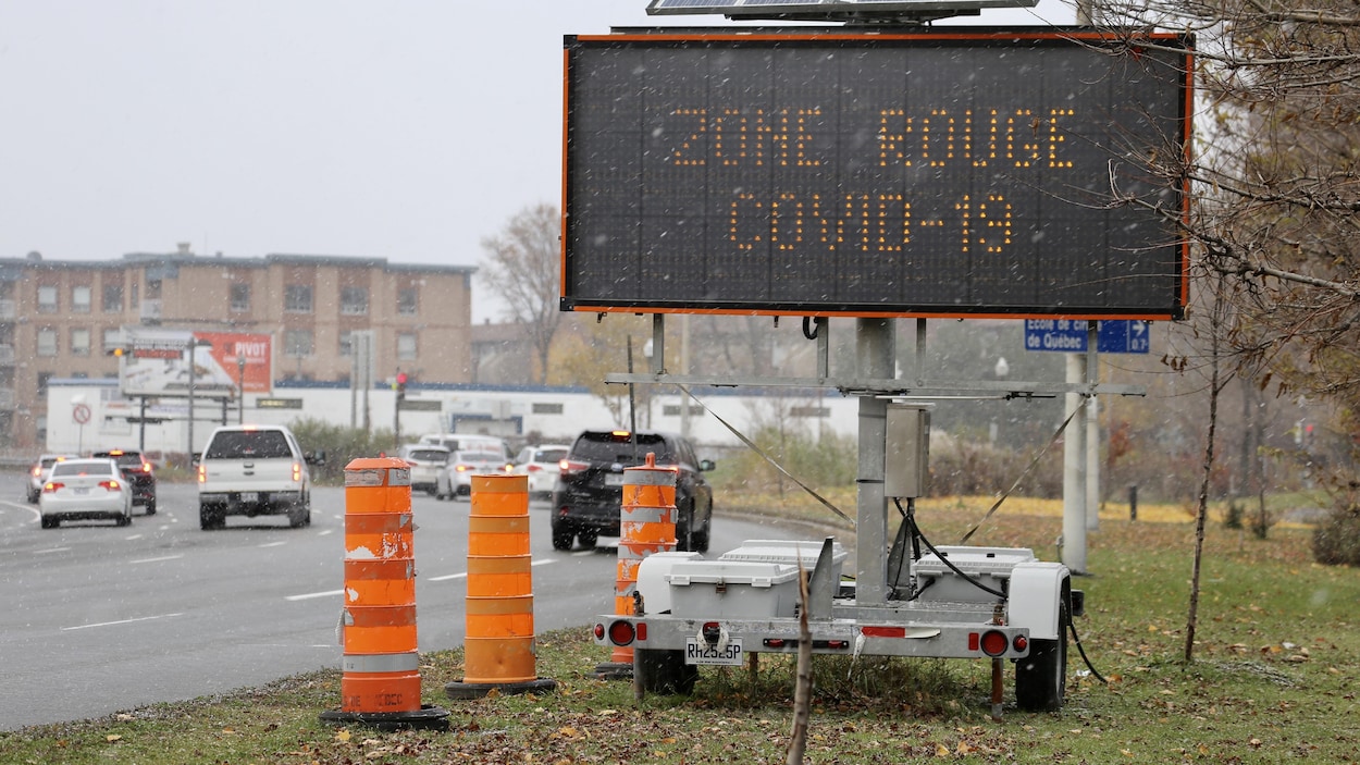 Un panneau lumineux de signalisation routière indique : « COVID Zone rouge ».